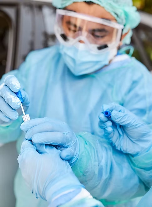 Collector in protective equipment preparing a specimen collection kit